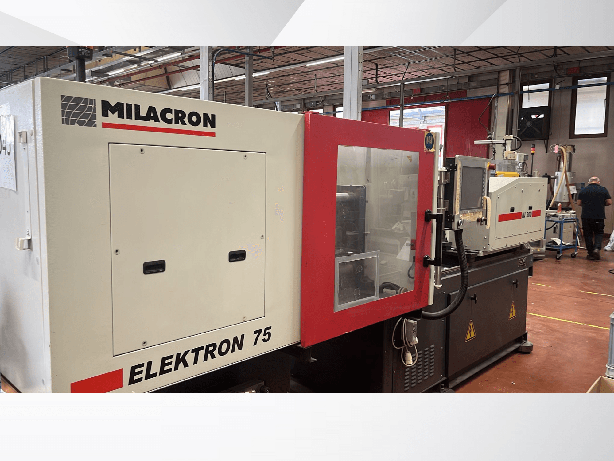 Máquina de moldeo por inyección Milacron Elektron 75 en un taller, vista lateral mostrando su panel de control y piezas mecánicas.