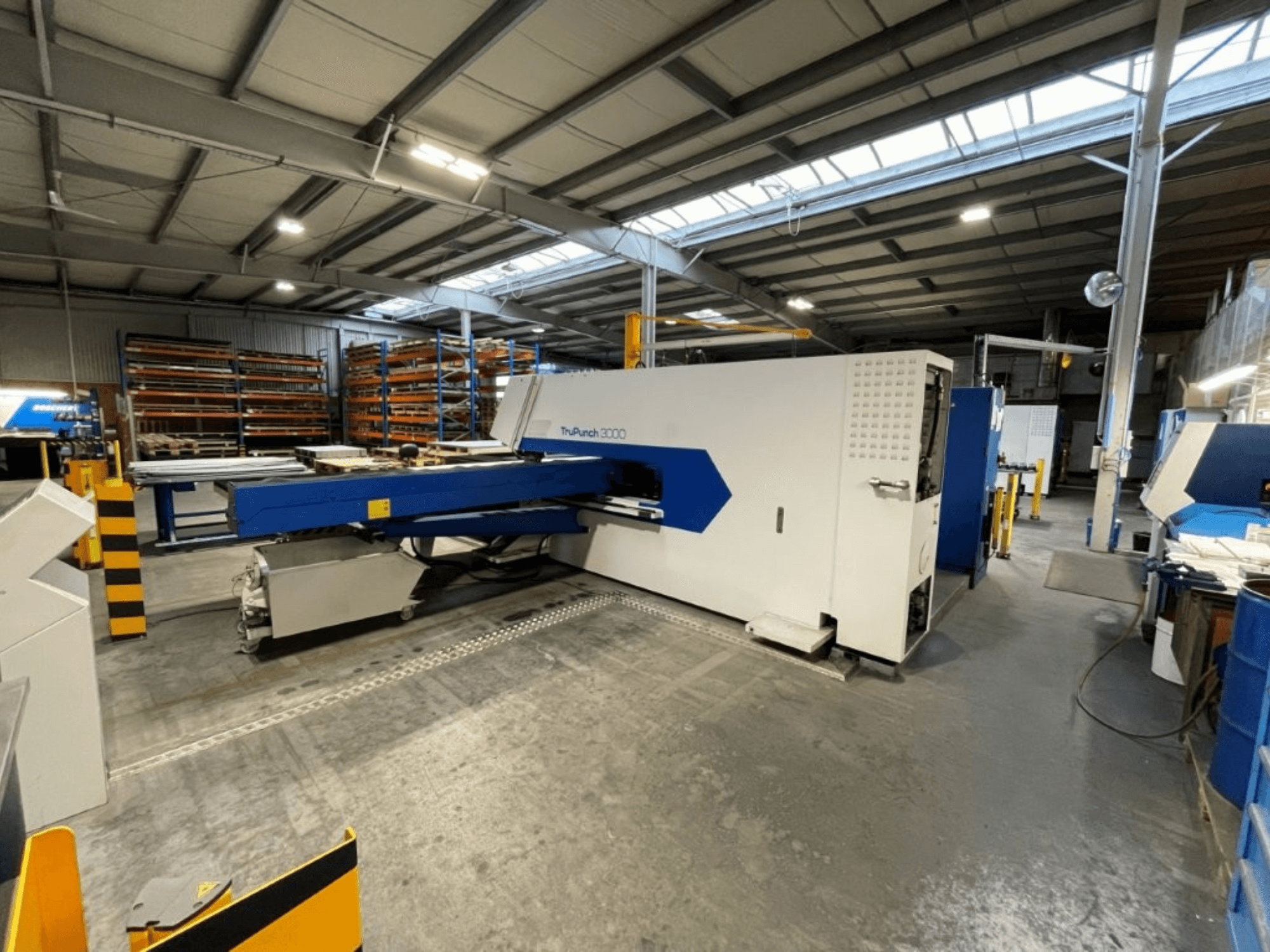 La punzonadora CNC TRUMPF TruPunch 3000 en un entorno industrial; la vista frontal muestra su diseño en azul y blanco y sus componentes operativos.