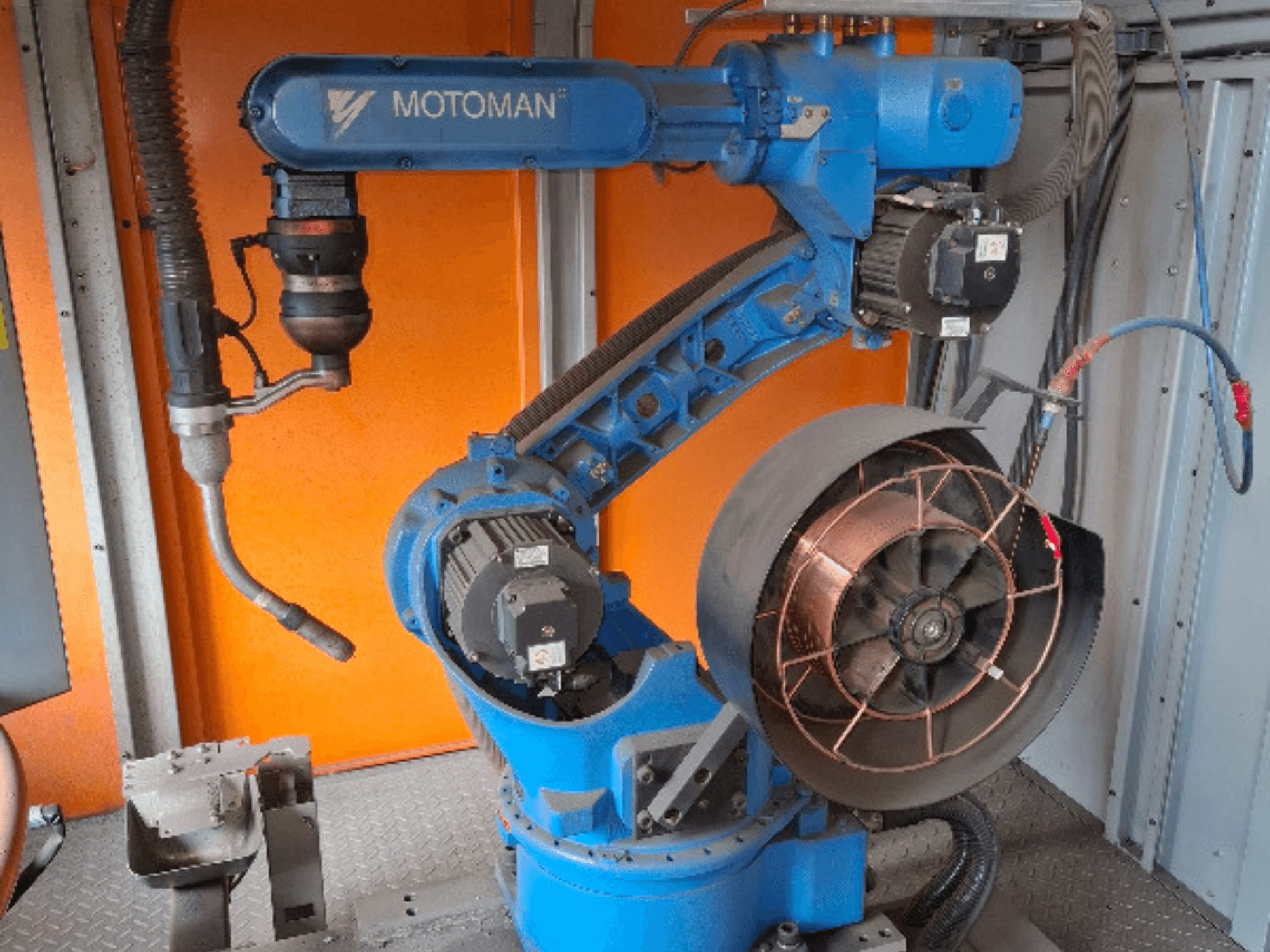 Brazo robótico MOTOMAN en azul, vista lateral, con ventilador y utillaje acoplados, mostrando detalles mecánicos y conexiones.