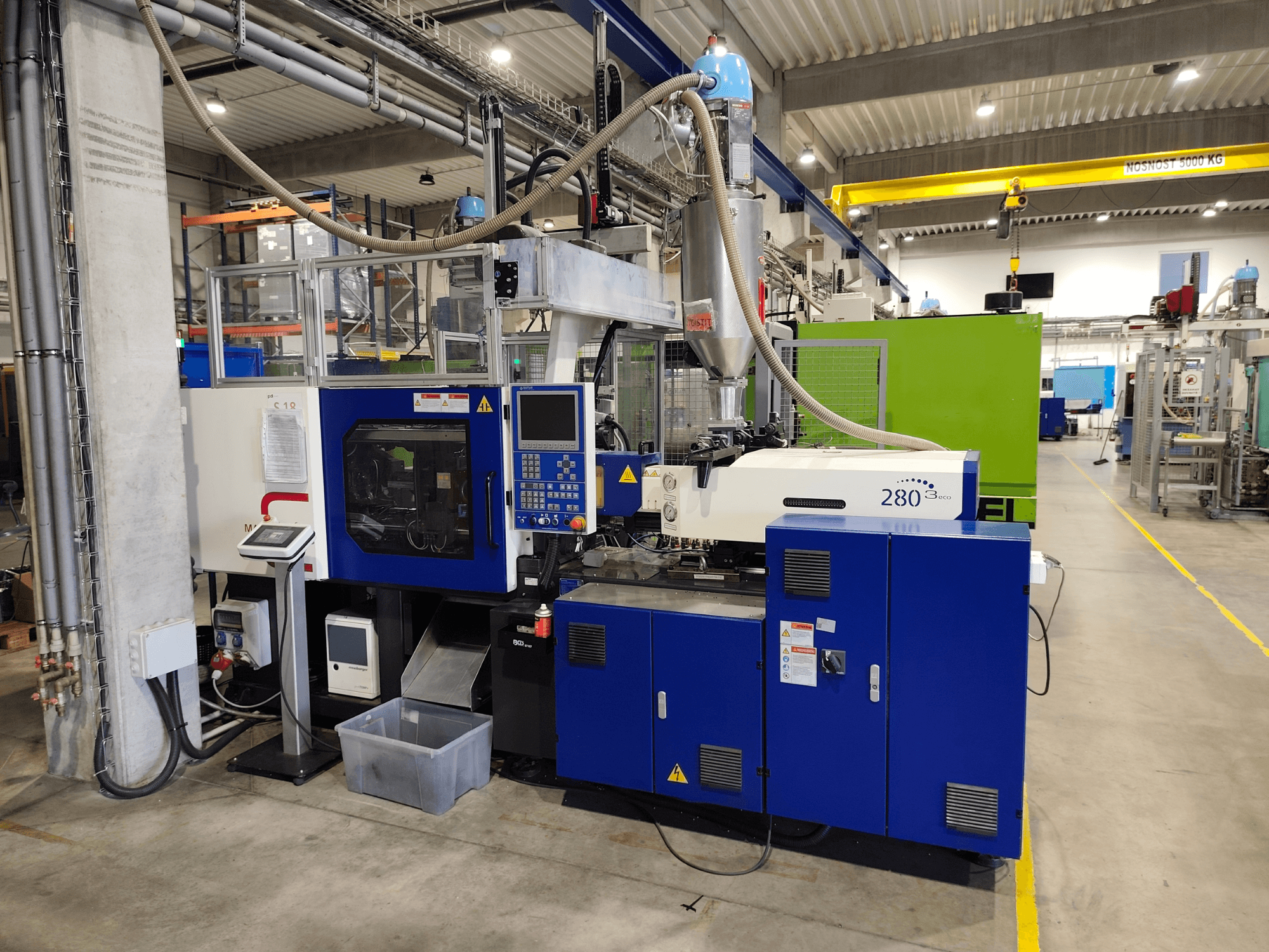 Máquina de moldeo por inyección hidráulica HAITIAN Mars III MA 900/280 A ECO, vista lateral, en la que se aprecian los mandos y la unidad de alimentación.