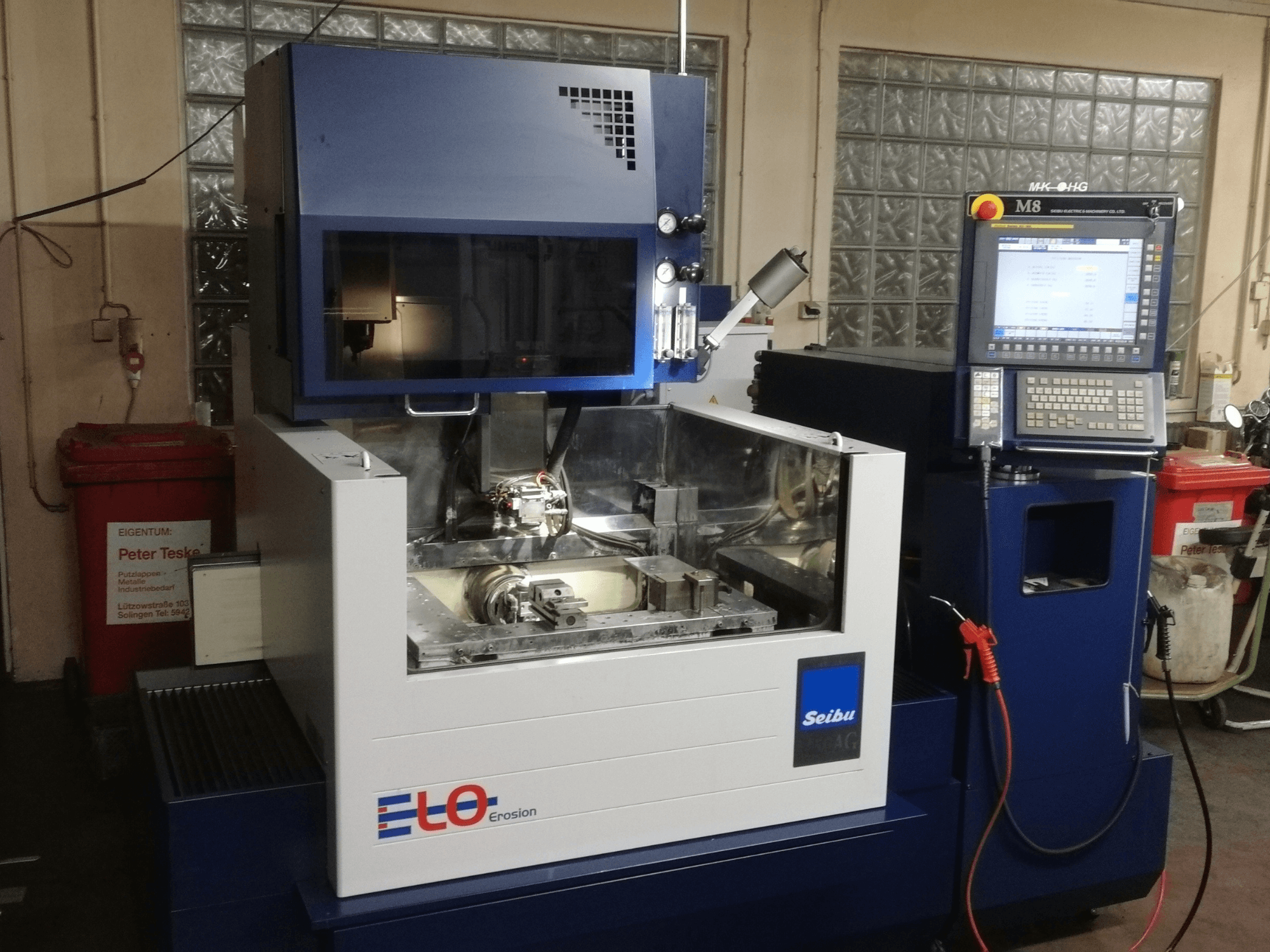 Máquina de erosión ELO Seibu vista de frente, con panel de control y zona de trabajo visible con componentes metálicos.